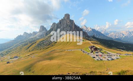 Majestätische Berge umgeben den Giau Pass in den Dolomiten, Italien, mit sanften Wiesen und üppigem Grün unter einem teilweise bewölkten Himmel während Stockfoto