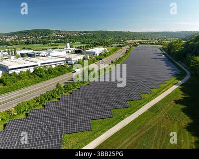 Luftdrohnenfoto einer großen Reihe von Photovoltaik-Solarpaneelen neben der Autobahn Stockfoto