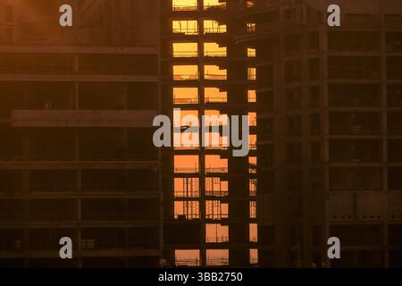 Baustelle bei Sonnenuntergang. Turmdrehkrane in Aktion. Wohngebäude und Immobilien. Kran während der Schalung. Stockfoto
