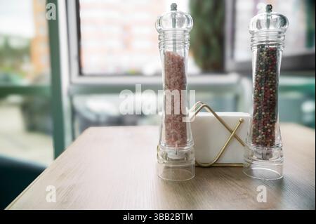 Salz- und Pfeffermühlen auf einem Holztisch und Papierservietten Stockfoto