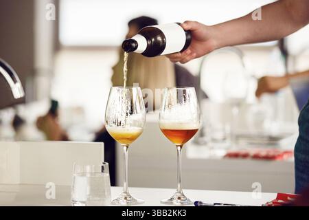 Bier aus der Flasche in das Glas während der Verkostung, Nahaufnahme. Stockfoto