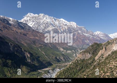 Annapurna III. Erhebt sich über dem Marsyangdi Valley auf dem Annapurna Circuit Trail zwischen Upper Pisang und Manang, Nepal, unter einem klaren blauen Herbsthimmel Stockfoto