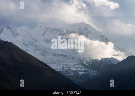 Annapurna II erhebt sich bei Sonnenaufgang hinter Wolken, vom Dorf Upper Pisang auf dem Annapurna Circuit Trail im Nepalaya aus gesehen Stockfoto