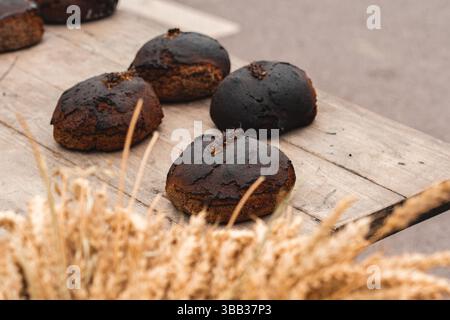 Hausgemachtes Schwarzroggen-Müsli-Brot mit Samen und Ohr von Mais oder Weizen auf einem Holztisch in einem traditionellen Straßenmarkt mit Weizenohren Stockfoto