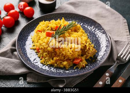 Teller mit leckerem Pilaw mit Rosmarin und Kirschtomaten auf dunklem Hintergrund, Nahaufnahme Stockfoto