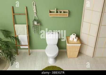Das Innere des stilvollen Toiletten mit Keramikschale, Papierrollen und Korb Stockfoto