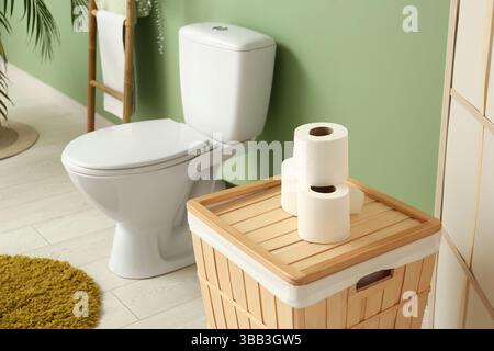 Das Innere des stilvollen Toiletten mit Keramikschale, Papierrollen und Korb Stockfoto