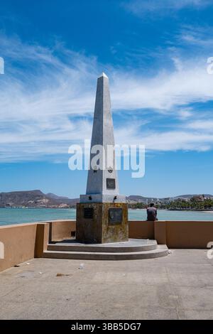 Ein Mann sitzt neben dem Obelisco a los Niños Héroes ist ein Denkmal an der Malecón in La Paz, BCS Mexiko. Stockfoto