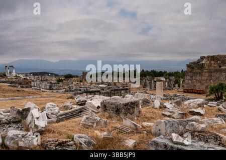Das Nymphaeum in Hierapolis ist eine Ruine aus Stein mit verstreuten Säulen und Blöcken, mit Blick auf die offene Ebene der antiken Stadt. Stockfoto