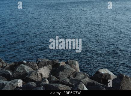 Ein friedlicher Blick auf das tiefblaue Wasser, das sanft an einer felsigen Küste plätschert. Stockfoto