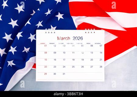 Tischkalender März 2026 und Flagge der Vereinigten Staaten von Amerika auf Holztisch, Flat Lay. Stockfoto