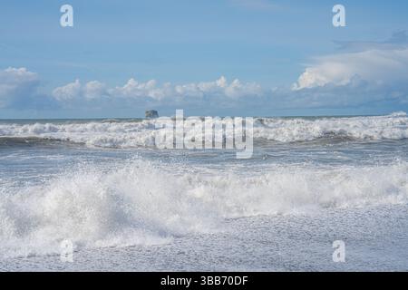 Stürzende Wellen des Pazifischen Ozeans Rollen unter einem hellblauen Himmel auf die Küste zu. Stockfoto