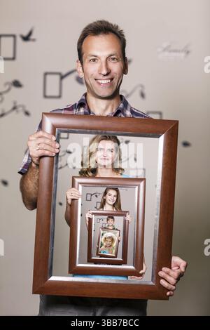Glücklicher Vater hält Porträt mit seiner Familie jeder befindet sich in ihren eigenen Rahmen Stockfoto