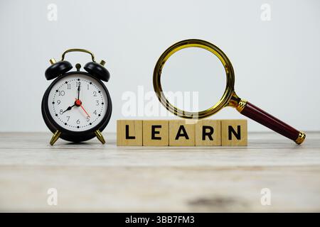 Zeit zum Lernen mit Holzblöcken Buchstaben und Lupenglas auf hölzernem Hintergrund Stockfoto