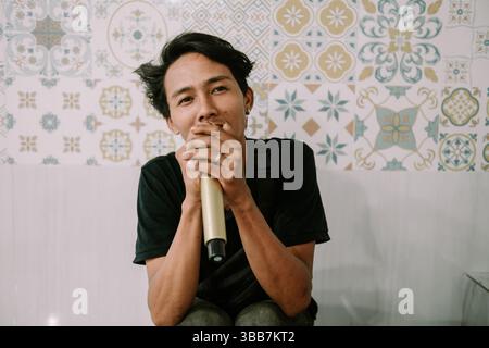 Junger asiatischer Mann, der ein Mikrofon hält, um auf der Bühne drinnen aufzutreten, das Konzept der Musikvorführung, des Talents, der Veranstaltung oder der Bühne Stockfoto
