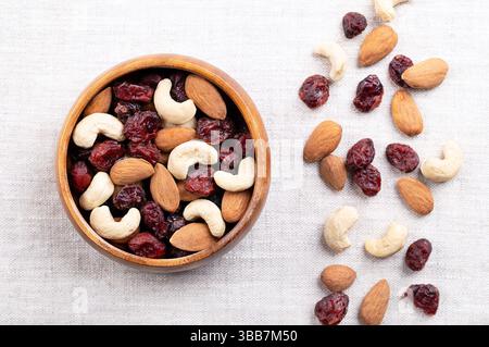 Cranberry Mandel Cashew Trail Mix in einer Holzschale auf Leinen. Getrocknete gesüßte Preiselbeeren mit rohen Mandeln und Cashewkernen. Beliebte Snacks. Stockfoto