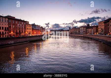 Urbane Szene bei Sonnenuntergang im Stadtzentrum von Pisa. Die Lungarni glänzen sanft an einem typischen Frühlingsabend. Stockfoto