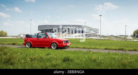 Red Volkswagen Golf mk2 Cabriolet in der Nähe der Arena Lviv. Seitenansicht des roten VW der 1990er Jahre, Stadion im Hintergrund. Stockfoto