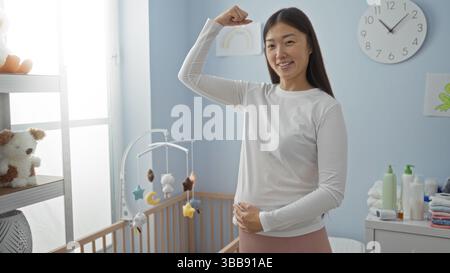 Frau, die selbstbewusst in einem gemütlichen Schlafzimmer in der Nähe der Babywiege steht und einen fröhlichen Ausdruck mit einem hellen Innenraum bietet, der ein einladendes Zuhause unterstreicht Stockfoto