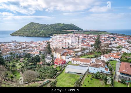Angra do Heroismo mit Halbinsel Monte Brasil im Hintergrund. Historische UNESCO-Weltkulturerbe-Stadt mit weißen Gebäuden, roten Ziegeldächern und Kolonialarchit Stockfoto