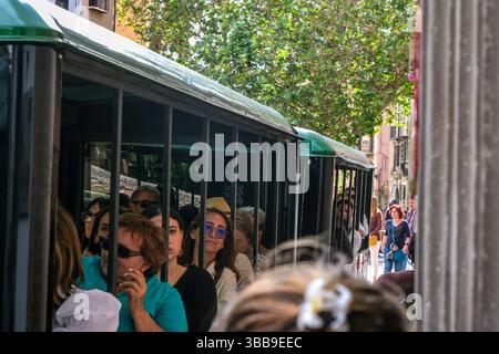 Ein Touristenbus fährt durch eine enge Straße von Fußgängern in Granada, Spanien Stockfoto