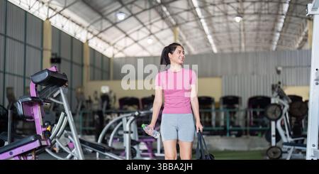 Workout und Fitness. Eine junge Frau lächelt nach dem Turntraining, trägt Tasche und Trinkflasche. Stockfoto