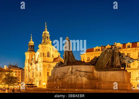 Jan-Hus-Denkmal die barocke St.-Nikolaus-Kirche und das Jan-Hus-Denkmal auf dem Platz Altstädter Ring in der Abenddämmerung, Prag, Tschechische Republ Stockfoto