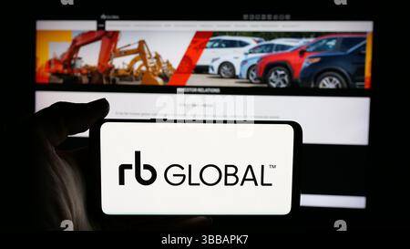 Stuttgart, Deutschland - 27.12.2024: Person mit Mobiltelefon mit Logo der Firma RB Global Inc. (Ritchie Bros. Auktionatoren) auf dem Bildschirm angezeigt Stockfoto