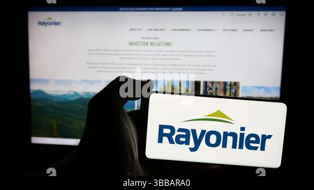 Stuttgart, Deutschland - 27.12.2024: Person, die ein Mobiltelefon mit dem Logo des amerikanischen Holzreit-Unternehmens Rayonier Inc. Auf dem Bildschirm hält Stockfoto