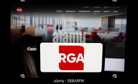 Stuttgart, Deutschland - 27.12.2024: Person mit Mobiltelefon mit Logo der US-amerikanischen Rückversicherung Group of America Inc. (RGA) auf dem Bildschirm Stockfoto