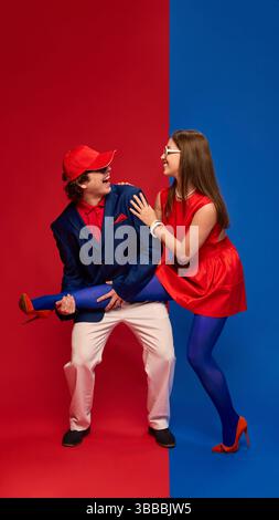 Verspielter junger Mann und Frau, Paar in Golf-inspirierten Outfits, die spielerisch interagieren, mit dem Mann, der das Bein hält, lachend Stockfoto