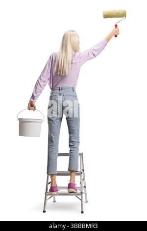 Rückansicht einer Frau auf einer Leiter, die eine Wand auf weißem Hintergrund malte Stockfoto
