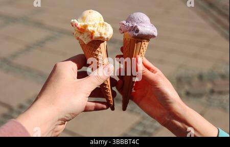 Zwei Hände halten zwei Eiskegel, Date, verliebtes Paar Stockfoto