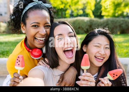 Drei glückliche Freundinnen machen ein Selfie, während sie im Sommer Eis essen Stockfoto
