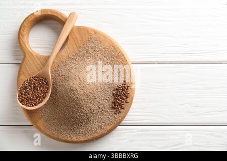 Leinsamenmehl und Löffel mit Samen auf weißem Holztisch, Draufsicht. Leerzeichen für Text Stockfoto