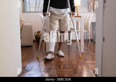 Patient, der Krücken benutzt, um zu Hause zu gehen, nachdem er sein Bein in einem Gips hatte Stockfoto