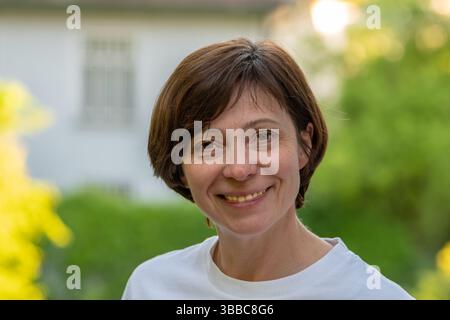 Porträt einer lächelnden Frau mittleren Alters vor grünem Hintergrund Stockfoto