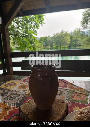 Tontopf auf einem Tisch mit malerischem Blick auf Bäume und Hügel von einem Balkon in Bosnien und Herzegowina. Mit Liebe. Stockfoto