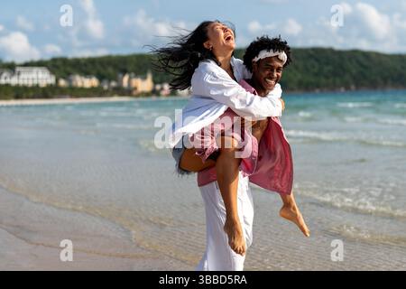 Interrassisches Paar, das einen romantischen Strandurlaub genießt und Liebe, Lachen und Zweisamkeit genießt Stockfoto