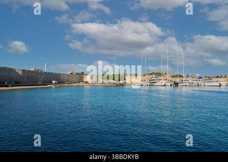 Kreta.Griechenland 15. Mai 2025: Malerischer Blick auf den Yachthafen von rhodos mit Luxusyachten, klarem blauem Wasser und alten Befestigungsanlagen unter einem teilweise bewölkten Sch Stockfoto