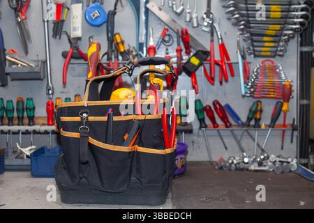 In der Werkstatt steht eine Elektrikertasche voller Werkzeuge. Stockfoto