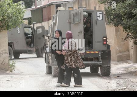 Nablus, Palästina. Mai 2025. Palästinensische Frauen weinen und rufen in der Nähe israelischer Militärfahrzeuge während der Militäroperation. Die israelische Armee umzingelte ein Gebäude während einer Militäroperation, bei der fünf Palästinenser getötet wurden, die sich darin verbarrikadiert hatten. In der Stadt Tammun, nördlich des Jordantals im Westjordanland, brach ein Feuerwechsel zwischen Palästinensern und der israelischen Armee aus. Quelle: SOPA Images Limited/Alamy Live News Stockfoto