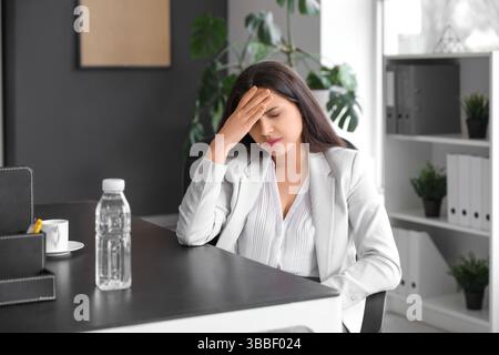 Junge Frau mit Kopfschmerzen im Büro Stockfoto