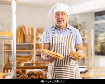 Älterer Mann Chef der Konditorei demonstriert Produkt aus Sortiment, Bocadillo auf Einwegplatten Stockfoto