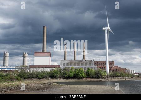 Windmühle und Schornsteine in Boston Mystic River - erneuerbare Energie trifft Industrie - MWRA Wilndmills Stockfoto