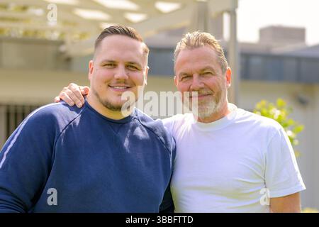 Porträt eines lächelnden Mannes mittleren Alters und eines älteren Mannes, der an einem sonnigen Tag im Freien nahe beieinander steht. Stockfoto