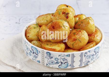 Gebackene neue Kartoffeln, mit Butter und Dill, auf einem weißen Teller, zu Hause, keine Leute Stockfoto