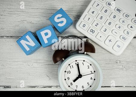 NPS-Text (Net Promoter Score) mit Wecker und Taschenrechner auf hölzernem Hintergrund Stockfoto