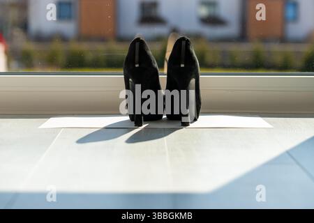 Schwarze Damen pumpen vor einem Fenster auf den Boden Stockfoto