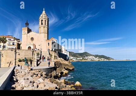 Sitges Spanien Kirche mit Blick auf das Mittelmeer mit Menschen, die entlang der Promenade spazieren gehen Stockfoto